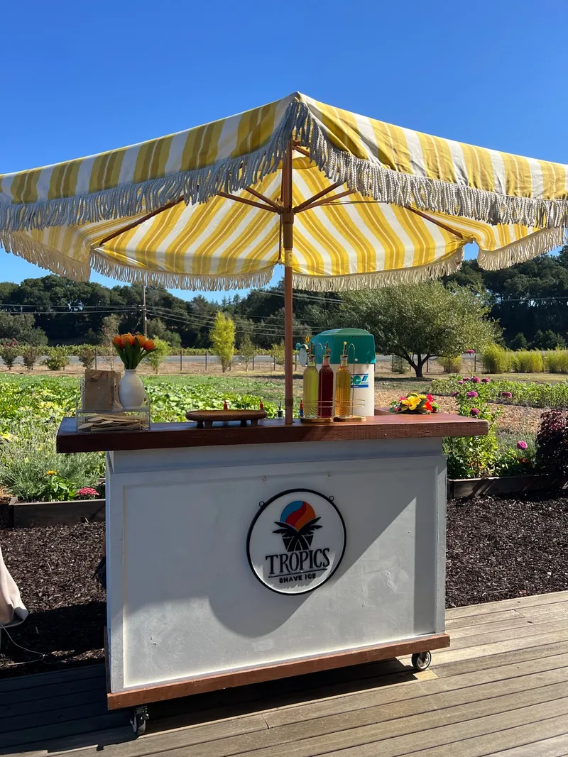 Tropics Shave Ice bar with a yellow striped umbrella and syrups