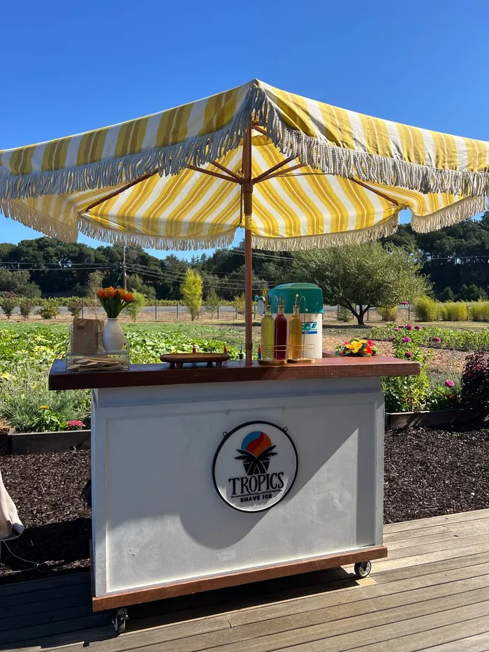 Tropics Shave Ice bar with a yellow striped umbrella and syrups